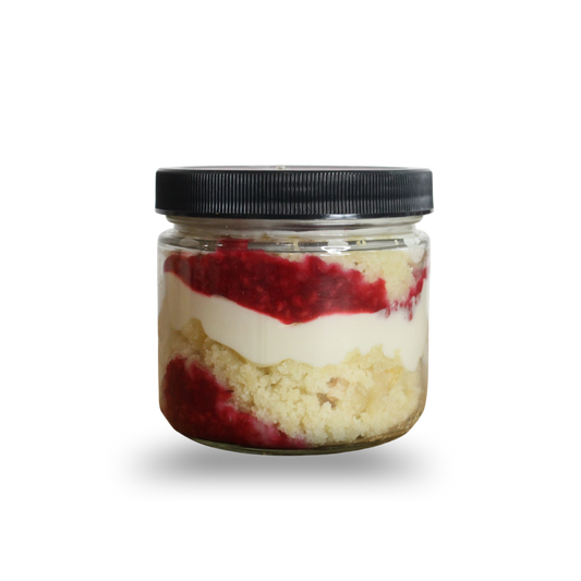 Layered dessert in a glass jar with a black lid on a white background