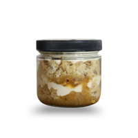 Jar of layered dessert with a black lid on a white background