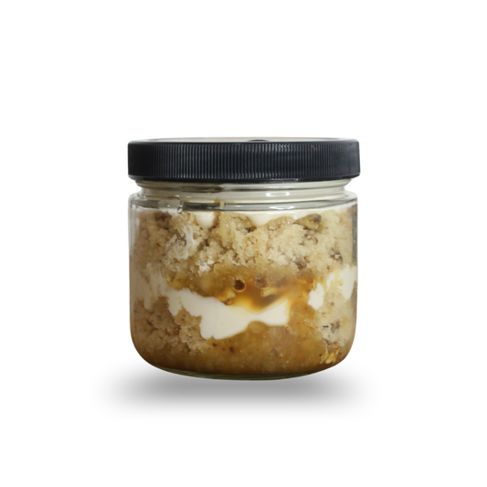 Jar of layered dessert with a black lid on a white background