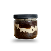 Jar with a black lid containing a dark brown substance on a white background